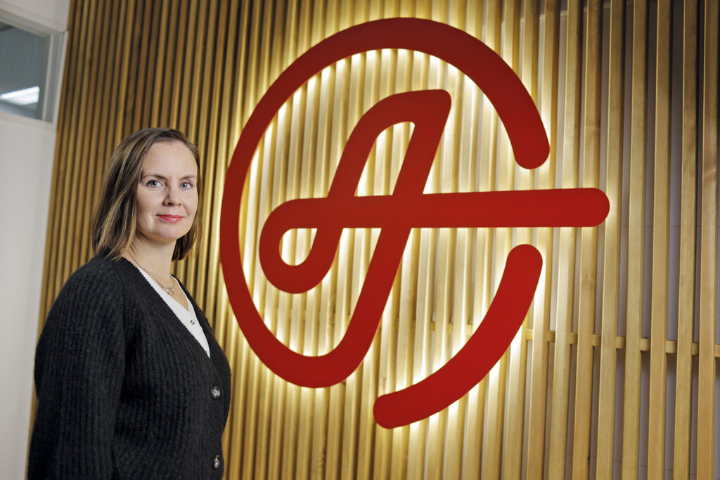 CEO Ida Saavalainen standing next to Ahola's logo.