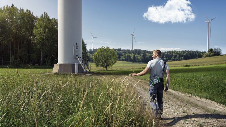 A man walks in a wind farm on a sunny day.