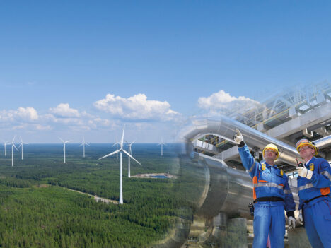 Two pictures merged into one. In the other picture, there is a wind farm photographed from the air on a sunny day. The second picture shows two employees standing next to each other at a plant.