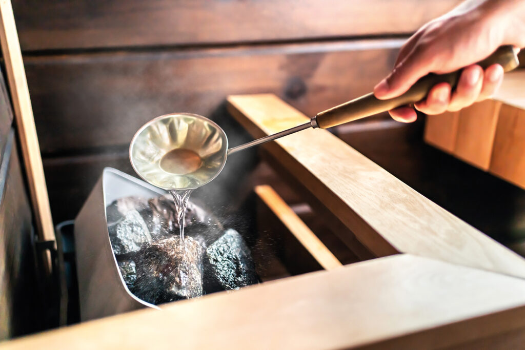 A person throwing water on a sauna stove.