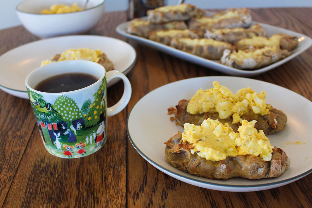 Karelian pies with egg butter on top and a Moomin mug full of coffee on a table.