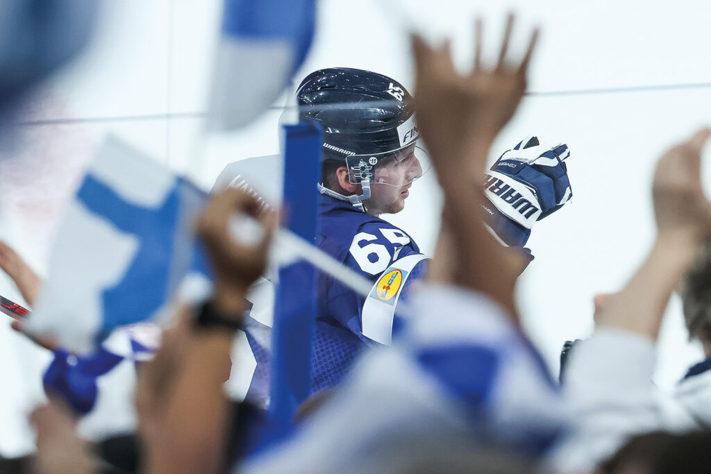 Finnish hockey player Sakari Manninen celebrates after a goal in the 2022 World Championships. Finnish flags waved by the fans in the front.