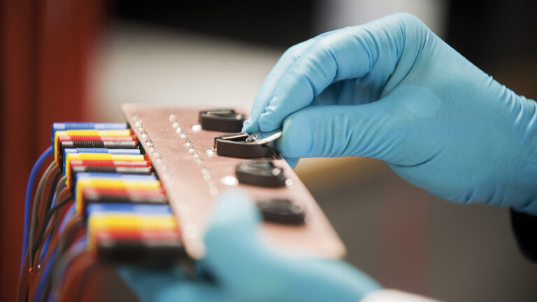 Battery cells held by a person with gloves on.