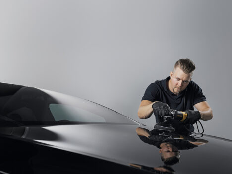 A man using a Mirka surface finishing product on a car.