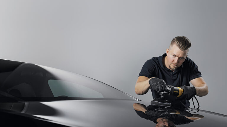 A man using a Mirka surface finishing product on a car.