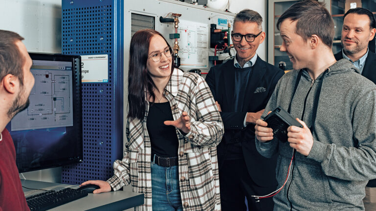 Novia's President Örjan Andersson and Dean at the Faculty of Technology and Seafaring Kristian Blomqvist photographed with three other people in a technological research environment.