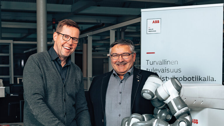 VAMK's Senior Lecturer Mika Billing and Director of the School of Technology Jorma Tuominen. They are standing behind two robotic arms.