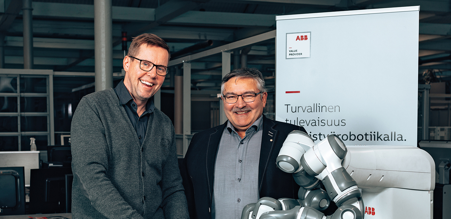 VAMK's Senior Lecturer Mika Billing and Director of the School of Technology Jorma Tuominen. They are standing behind two robotic arms.