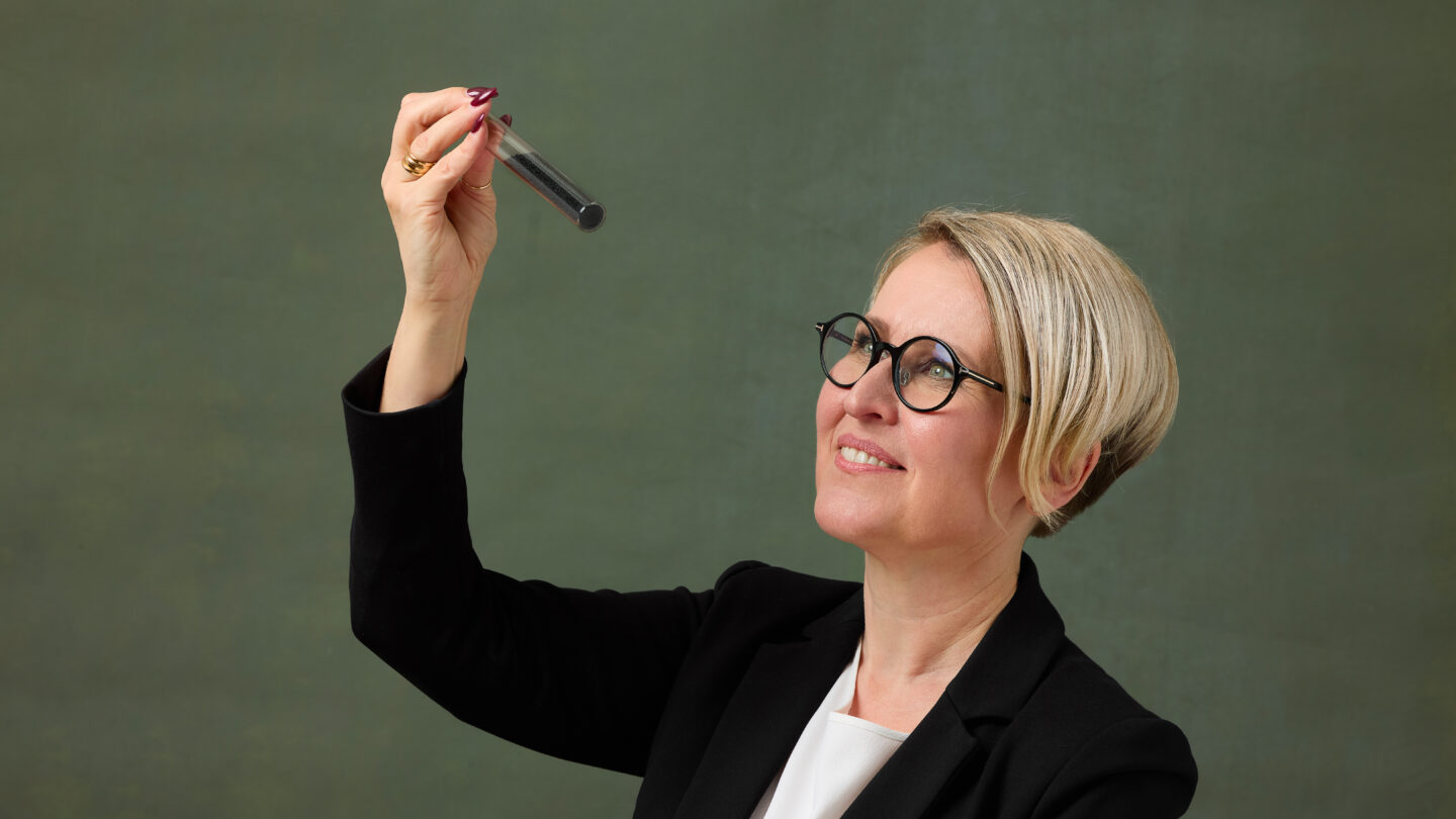 Laura Rahikka holding and looking at a test tube with carbon in it.