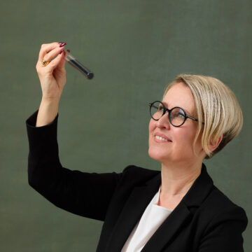 Laura Rahikka holding and looking at a test tube with carbon in it.