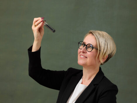 Laura Rahikka holding and looking at a test tube with carbon in it.
