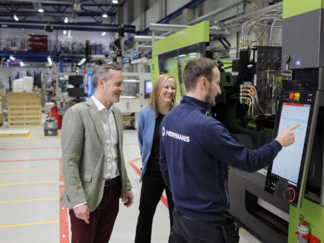 Dan Liljeqvist and Charlotte Sandström watching as Patrik Snellman uses a machine's touchscreen.