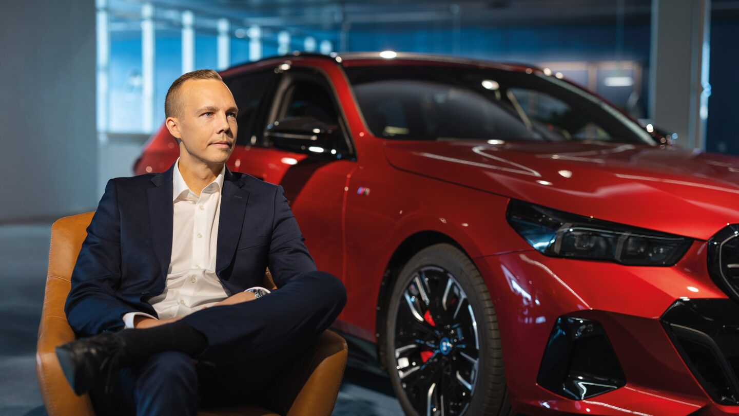 Henrik Pohjus sitting on a chair in front of a car.