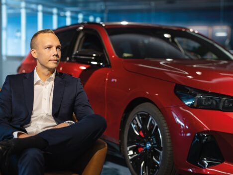 Henrik Pohjus sitting on a chair in front of a car.