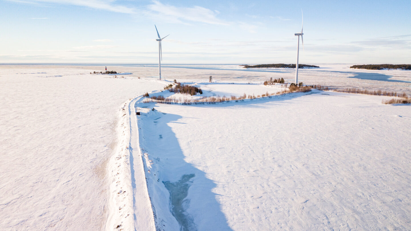 Two wind turbines on an island on a snowy day.