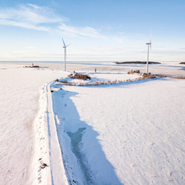 Two wind turbines on an island on a snowy day.