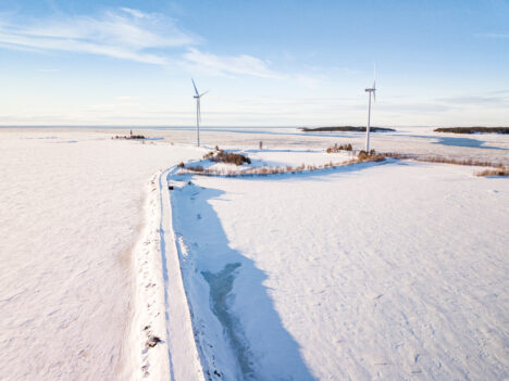 Two wind turbines on an island on a snowy day.